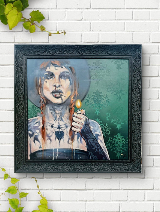 Framed artwork of a stylized portrait on a white brick wall with green leaves.
